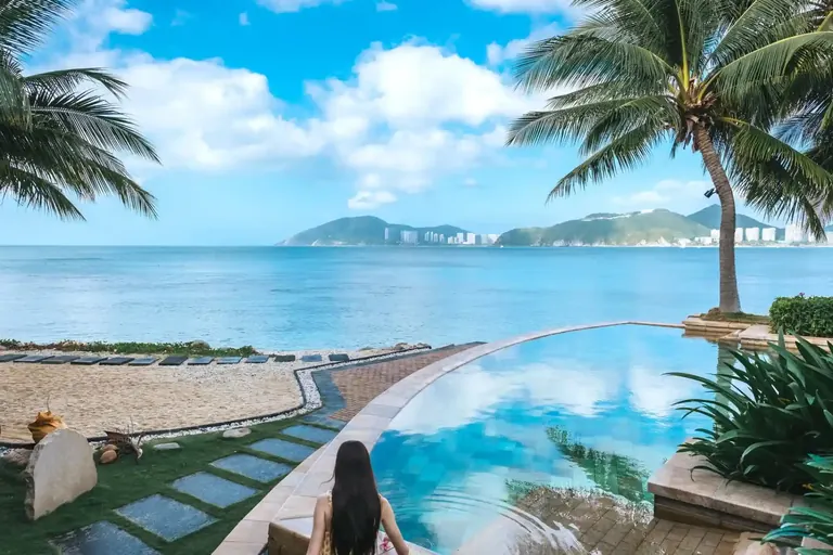 Palm-framed water and a resort pool, representative travel imagery
